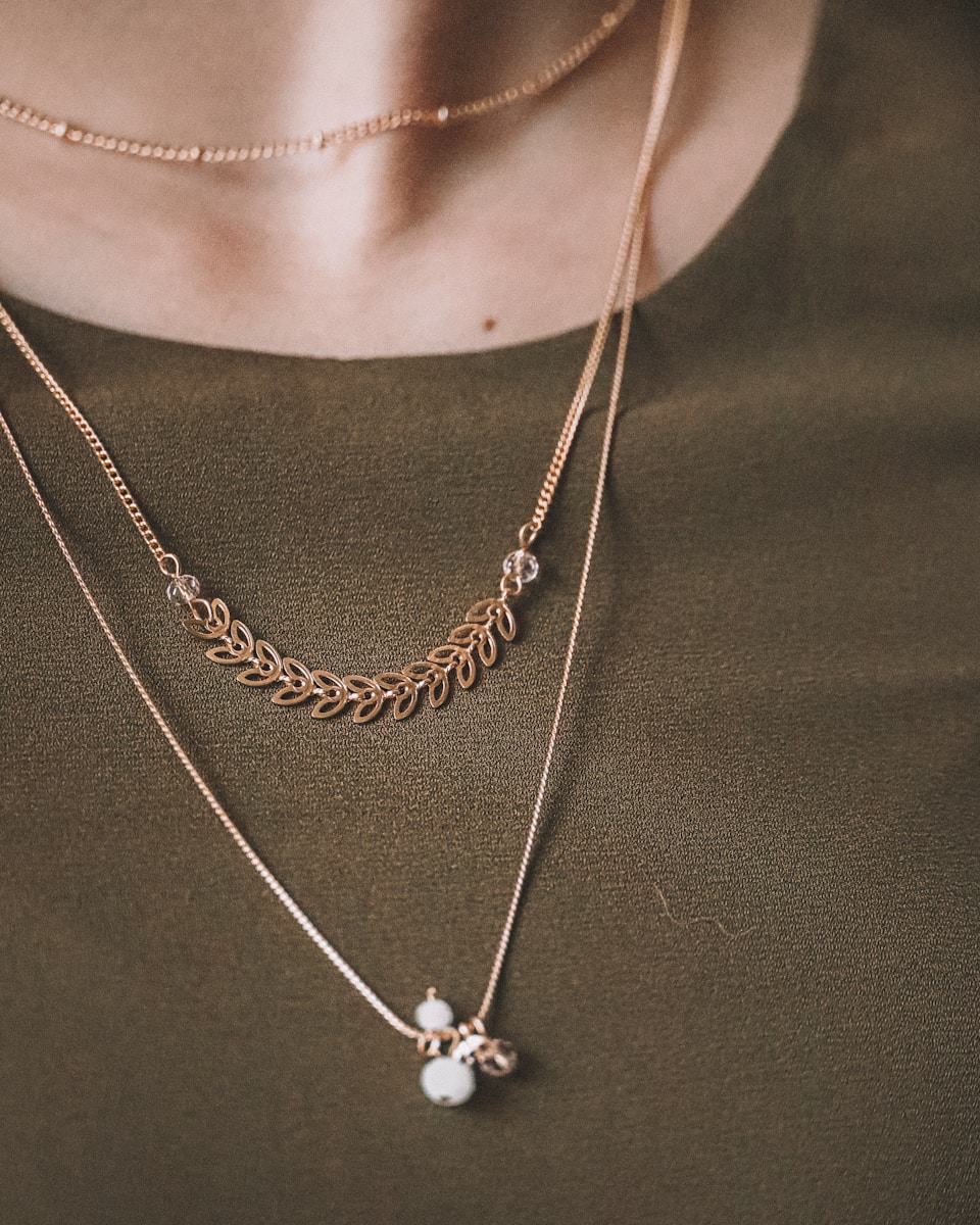 person wearing silver necklace with silver pendant